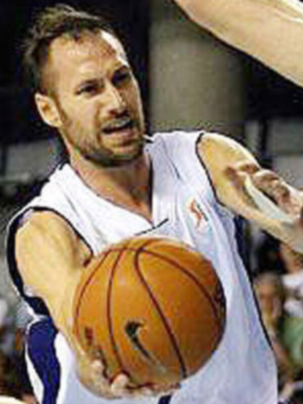Jugador de baloncesto en acción durante un partido, controlando el balón con intensidad.