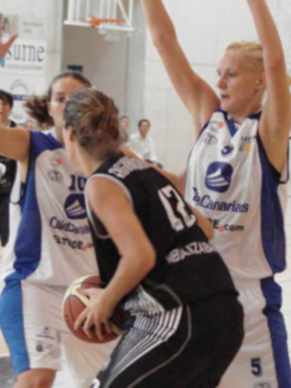Jugadoras de baloncesto en acción durante un partido, una defiende el balón mientras la otra intenta marcar.