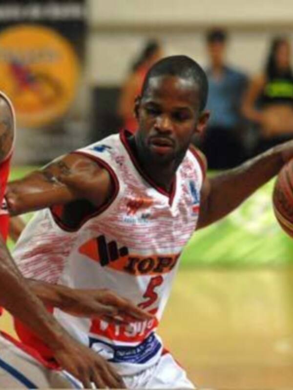 Jugador de baloncesto en acción durante un partido, controlando el balón con determinación.
