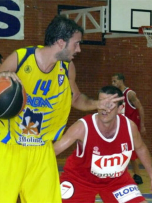 Jugadores de baloncesto en acción durante un partido, uno en amarillo y otro en rojo, en un entorno deportivo.