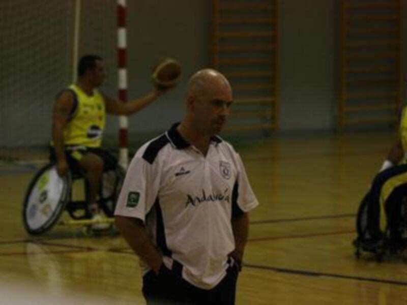 Jugadores de baloncesto en silla de ruedas en un partido en una cancha de baloncesto indoor.