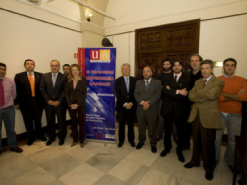 Una foto de grupo de personas en una reunión formal, con una pancarta que dice 'U' en el fondo.