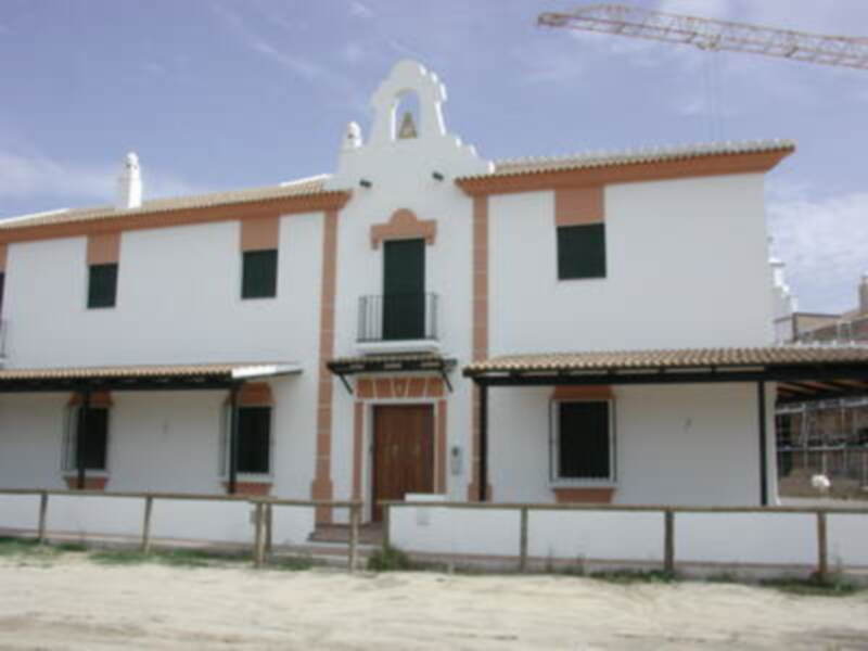 Vivienda tradicional con detalles arquitectónicos en blanco y rojo, ubicada en un entorno rural.