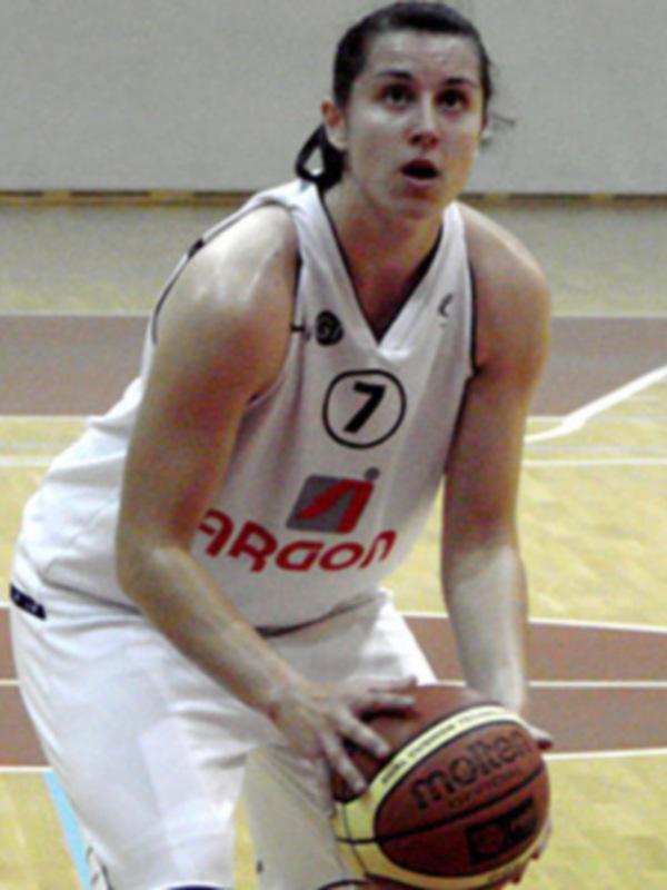 Jugadora de baloncesto en acción, controlando el balón en un partido de interior.