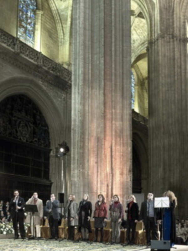 Concierto coral en la Catedral de Toledo, España, con una audiencia atenta y un escenario iluminado.