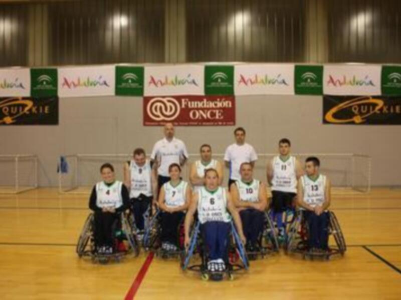 Equipo de baloncesto en silla de ruedas posando en una cancha deportiva.