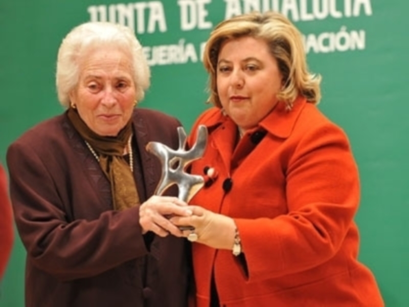 Una mujer entrega un premio a otra mujer en un evento formal.
