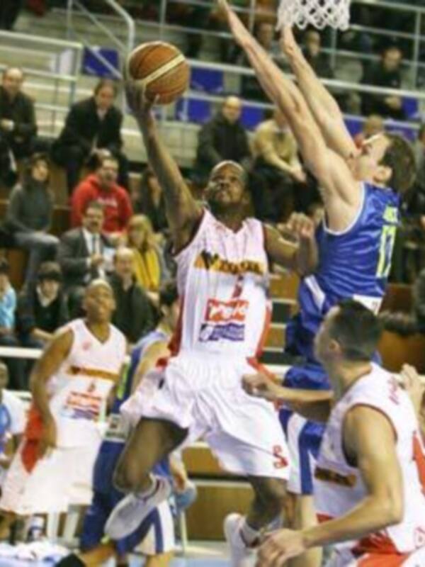 Jugador en acción durante un partido de baloncesto, intentando anotar en el aro.