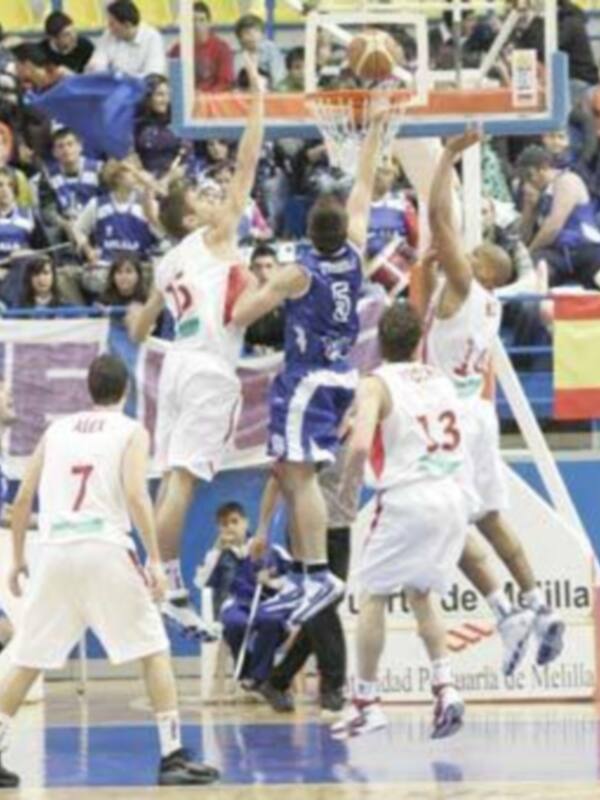 Jugadores de baloncesto en acción durante un partido, intentando anotar en el aro.