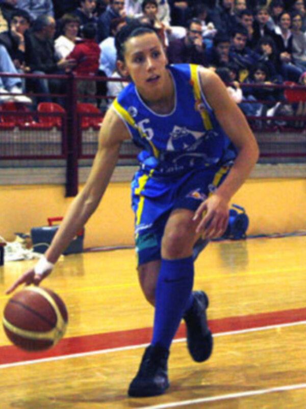 Jugador de baloncesto en acción durante un partido, driblando con destreza en el piso de un estadio lleno de espectadores.