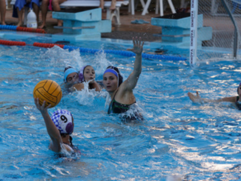 Jugadoras de waterpolo en acción durante un partido en una piscina.
