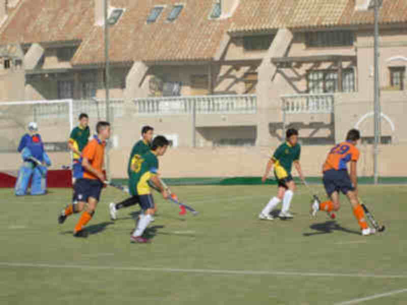 Jugadores de hockey sobre césped en acción durante un partido en un campo deportivo al aire libre.