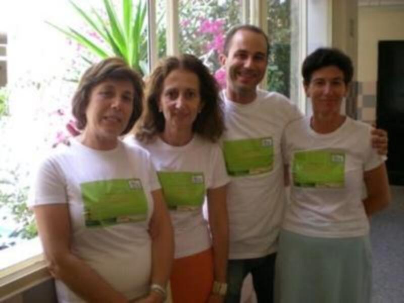 Personas con camisetas verdes en una habitación con plantas y ventana