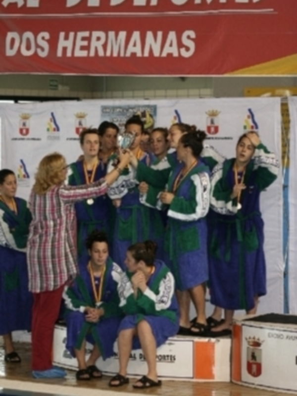 Equipo de natación recibiendo medallas en el podio de un evento deportivo.