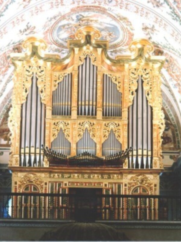 Organo barroco dorado en una iglesia, con detalles ornamentales y teclas visibles.