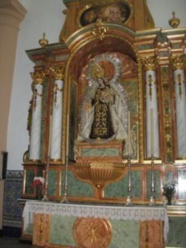 Altar ornamental con estatua de la Virgen María en un entorno religioso, decorado con dorado y marmolado.