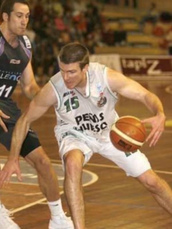 Jugador de baloncesto en acción durante un partido, driblando el balón con habilidad en un entorno deportivo.