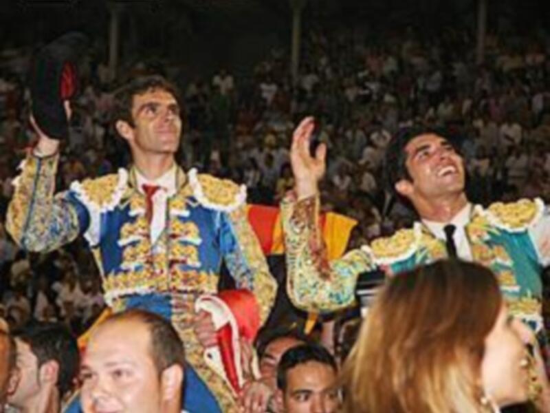 Festejos taurinos en España: toreros celebrando en el ruedo ante un público entusiasta.