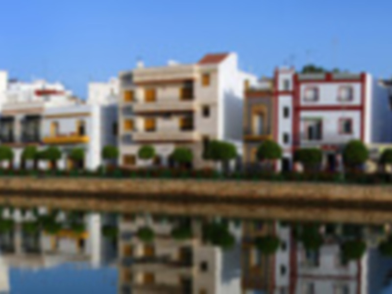 Vistas de edificios residenciales en un entorno de agua, con un cielo azul claro y un horizonte con edificios blancos y rojos.
