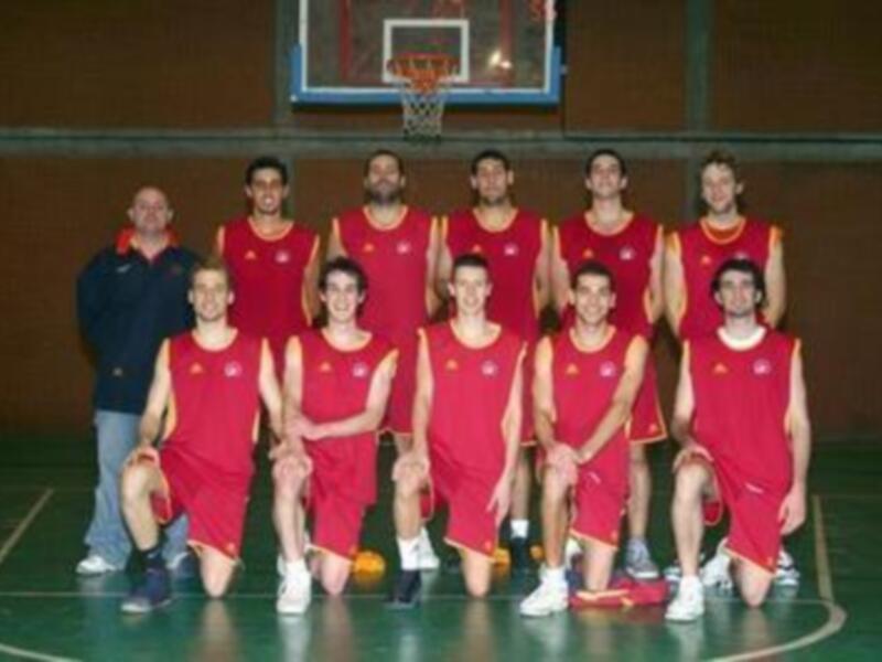 Equipo de baloncesto en uniforme rojo, posando en el campo de juego.