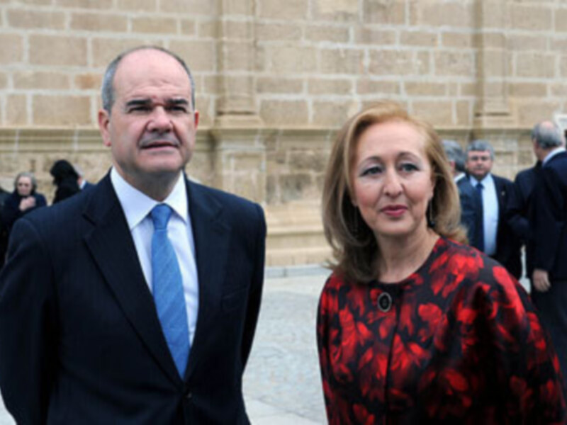 Dos personas en trajes formales posan frente a un edificio histórico.