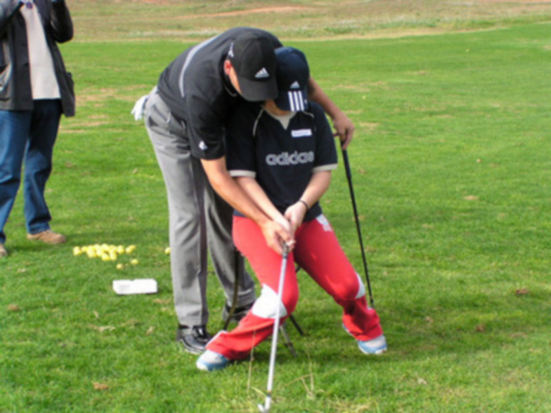 Persona en acción durante un entrenamiento de golf en un campo verde.
