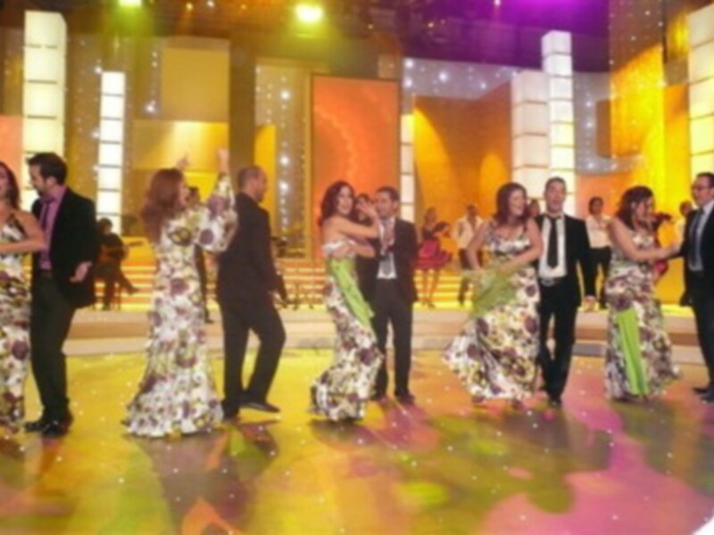 Cena de gala con invitados vestidos de gala bailando en una escena festiva y elegante.