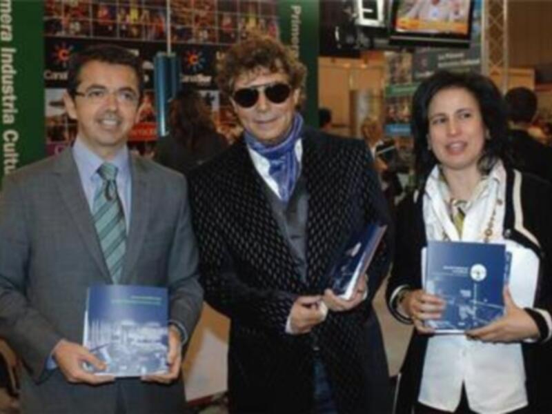 Tres personas posando con libros en una feria de libros.