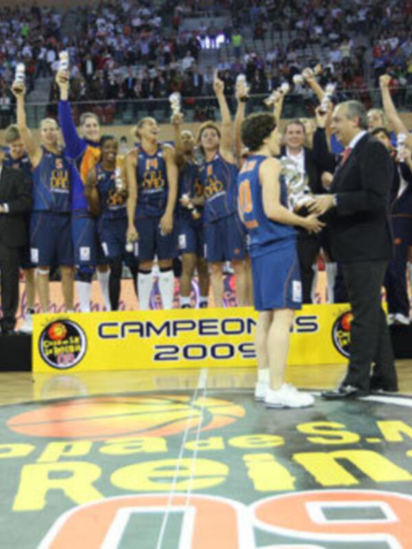 Equipo de baloncesto celebrando el título de campeón en un estadio lleno de espectadores.