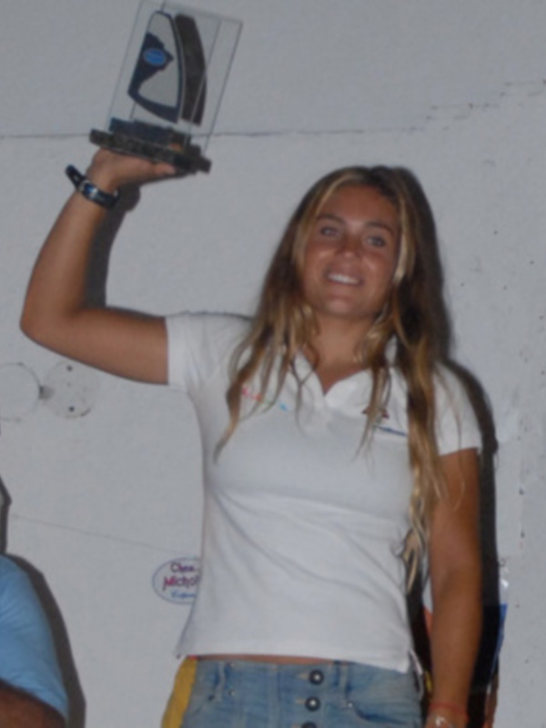 Persona sonriente levantando un trofeo en un ambiente interior.