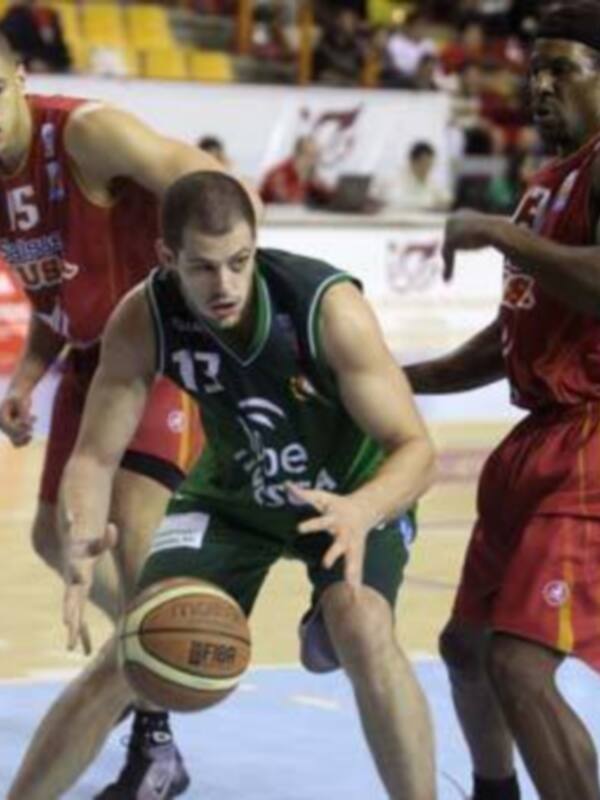 Juego de baloncesto en un estadio lleno, con jugadores en acción.