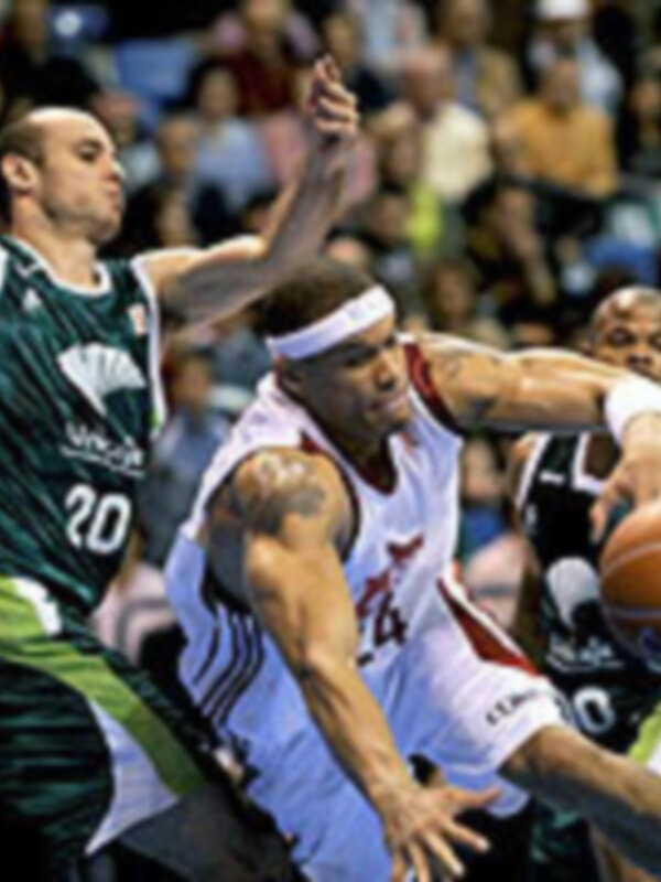 Jugadores de baloncesto compiten intensamente durante un partido en una cancha deportiva.
