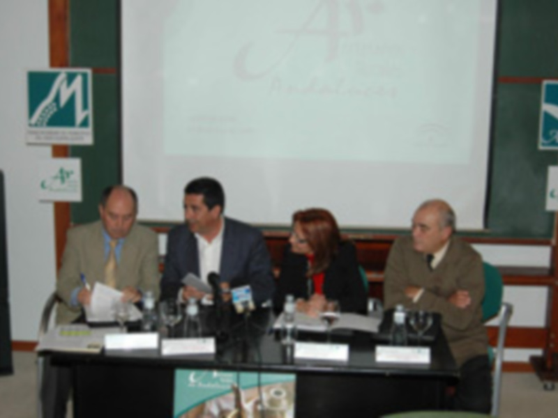 Conferencia de prensa con cuatro participantes sentados en una mesa con micrófonos, presentando ante un fondo de pantalla con el logo de la organización.