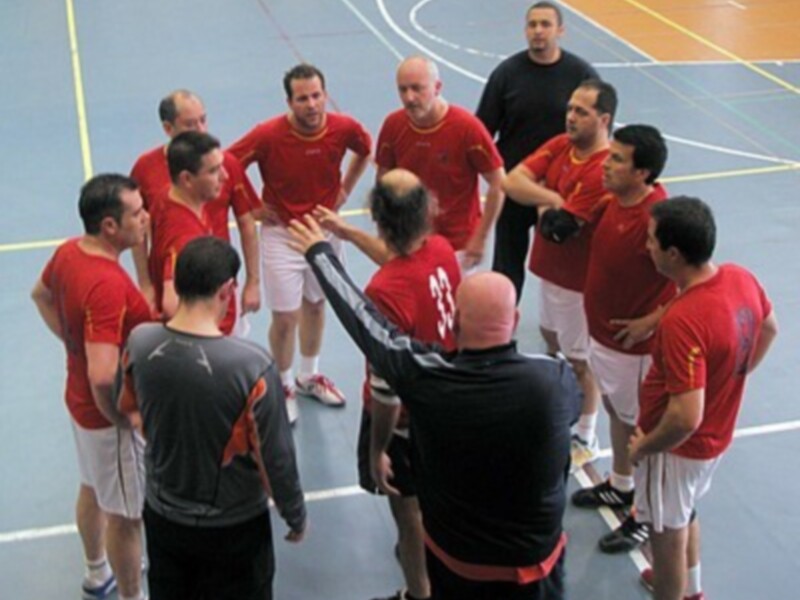 Equipo de balonmano en una reunión táctica en el aro de un gimnasio.