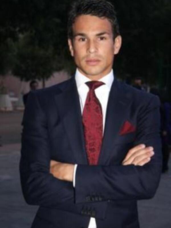 Un hombre vistiendo un traje azul con una corbata roja y un pañuelo en el bolsillo.