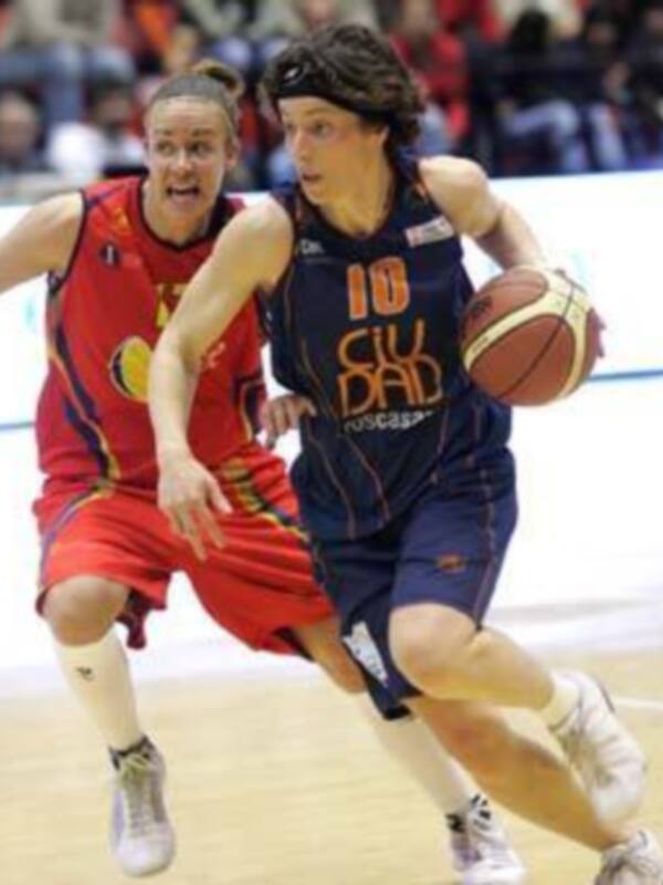 Jugadoras de baloncesto en acción durante un partido, una en rojo y otra en azul, en un entorno deportivo.