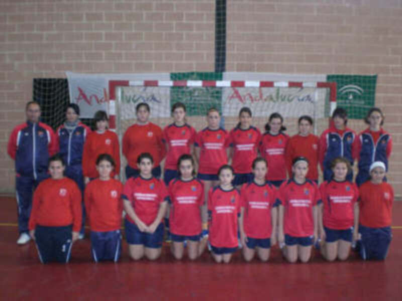 Equipo de fútbol sala femenino en uniforme rojo y azul, posando en una cancha deportiva.