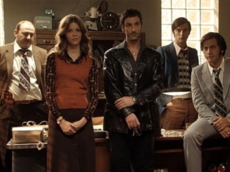 Personajes en una escena de la serie 'The Sopranos', vestidos con ropa de los años 70, en un interior acogedor.