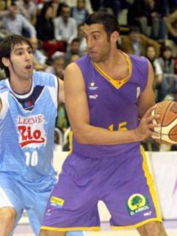 Un jugador de baloncesto en acción, con una camiseta azul y blanca y otro en una camiseta púrpura y amarilla.