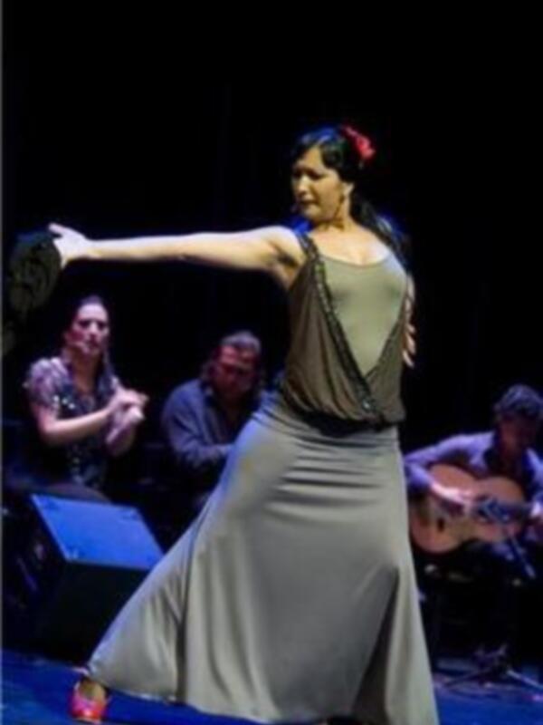 Arte flamenco en vivo: bailarina en movimiento con músicos en el fondo.