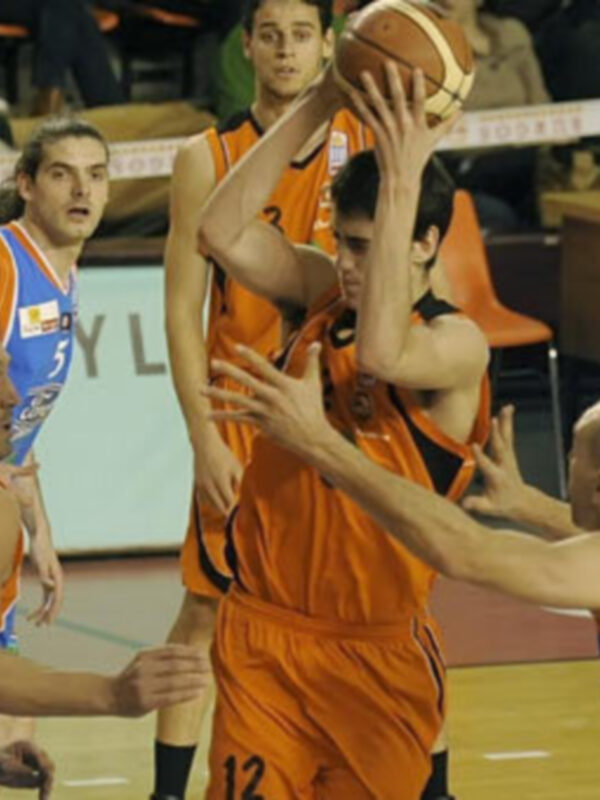 Jugadores en plena acción durante un partido de baloncesto, con un jugador en el centro lanzando el balón.