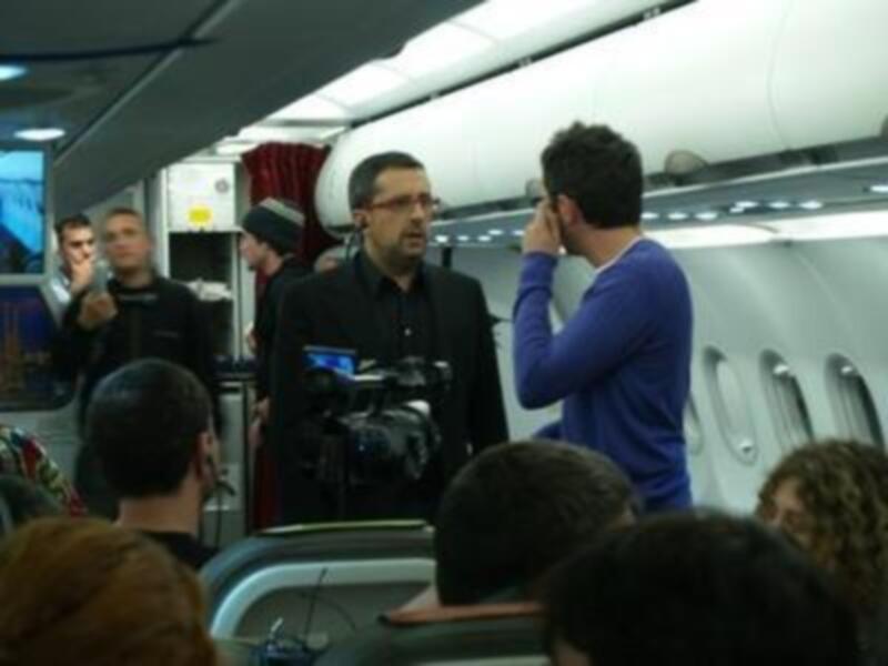 Reportero entrevistando a pasajero en el interior de un avión durante un vuelo.