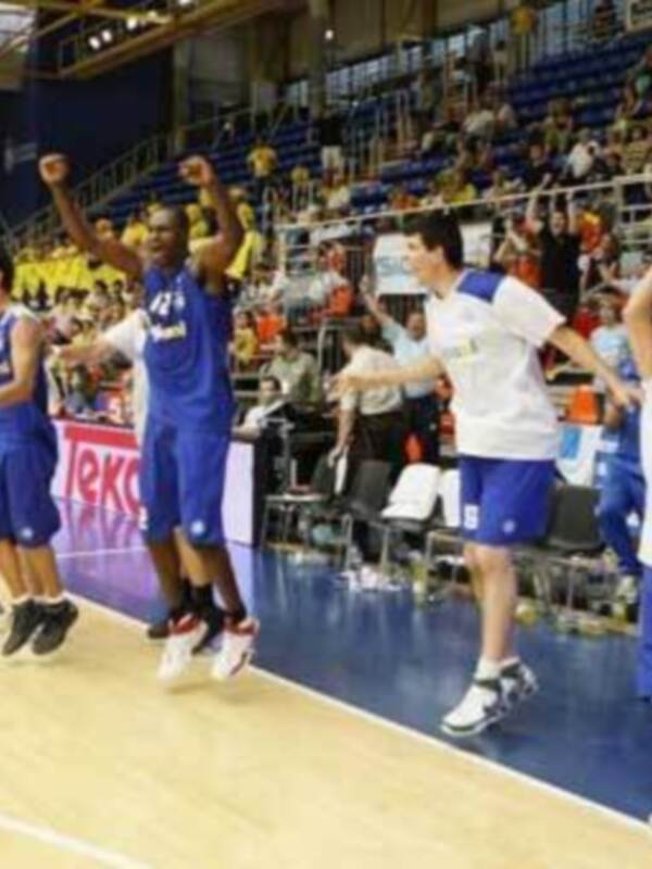 Equipo de baloncesto celebrando victoria en el pabellón deportivo.