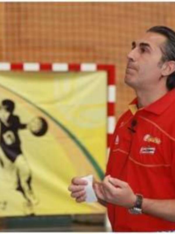 Entrenador de balonmano en una sala deportiva, preparándose para dar instrucciones.