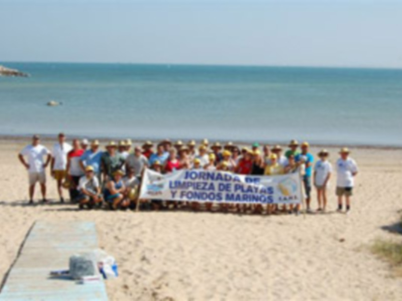 Gente en la playa con una pancarta que dice 'Jornadas de Limpieza de Playas y Fondo Marino'.