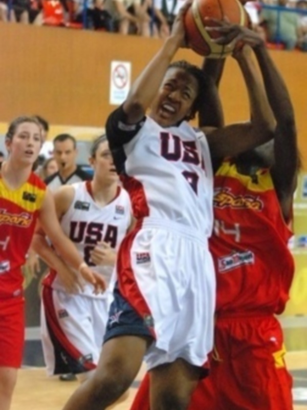 Jugador de la selección de baloncesto de Estados Unidos en acción durante un partido, luchando por el balón con un rival en el aro.