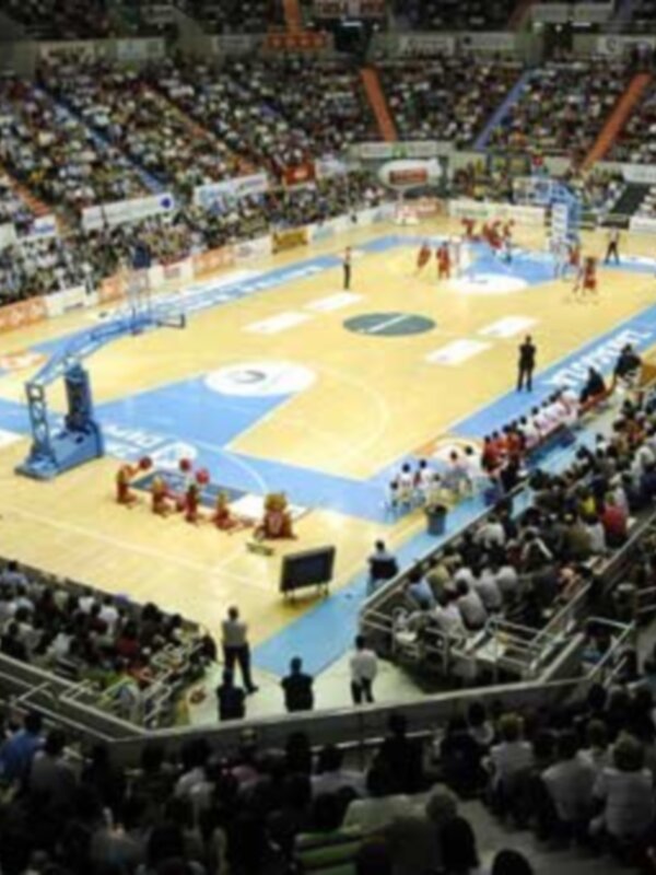 Juego de baloncesto en un estadio lleno de espectadores.