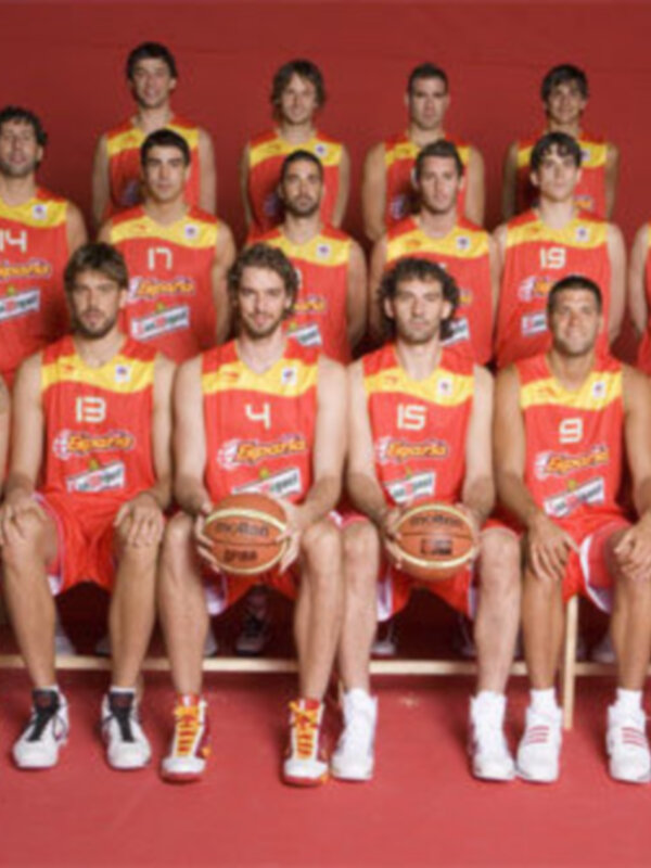 Equipo de baloncesto en uniformes rojos y amarillos, posando en fila para una foto oficial.