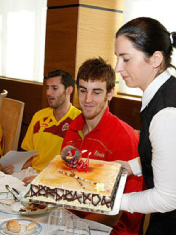 Una camarera sirve una tarta decorada con la bandera de España en un evento festivo.