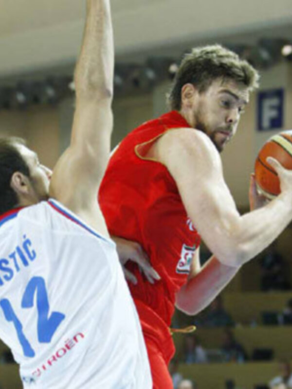 Jugador en rojo lucha por el balón durante un partido de baloncesto.